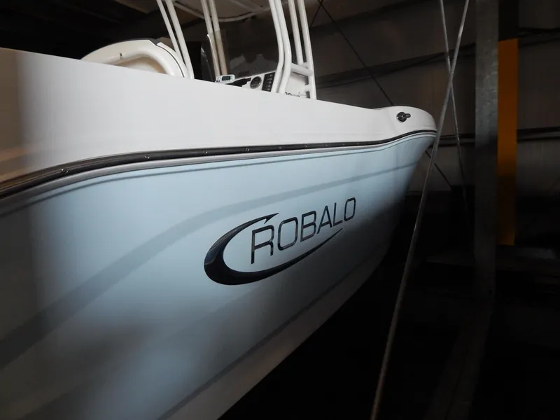 Slide: The Image of 2019 Robalo R202 Explorer boat in storage, side view with logo visible. - 7