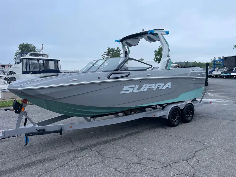 Slide: The Image of 2025 Supra SL boat on trailer in marina setting. - 1