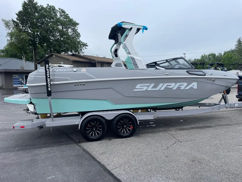 Slide: The Image of 2025 Supra SL boat on trailer, gray and teal design, parked outdoors. - 4