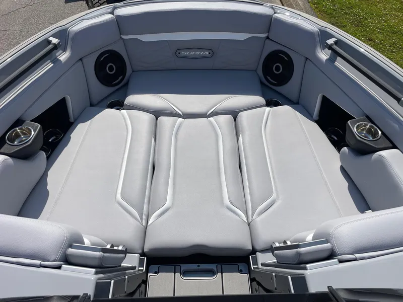 Slide: The Image of 2025 Supra SL boat interior with gray seating, cup holders, and speakers. - 5