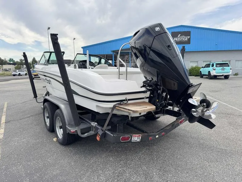 Slide: The Image of 1999 MasterCraft Powerstar 200 boat on trailer, parked in lot near blue building. - 10