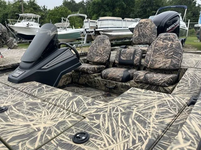 Slide: The Image of 2024 Lowe Stinger 175C boat with camouflage seats and Mercury engine, parked among other boats. - 12