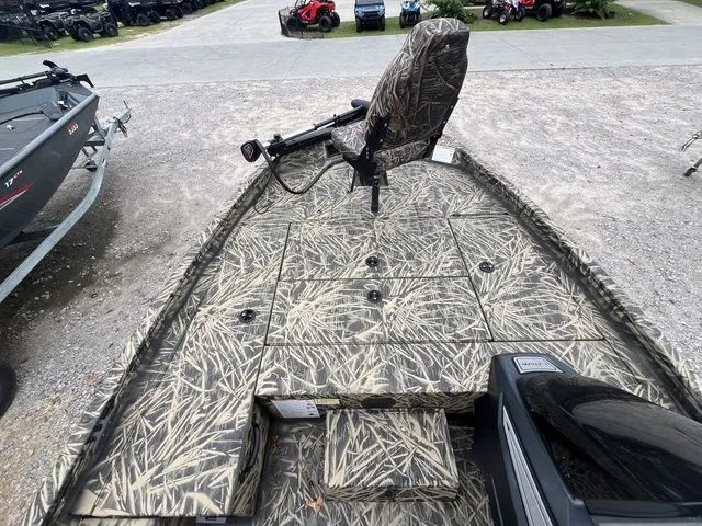 Slide: The Image of 2024 Lowe Stinger 175C boat with camo seating and deck, parked outdoors. - 14