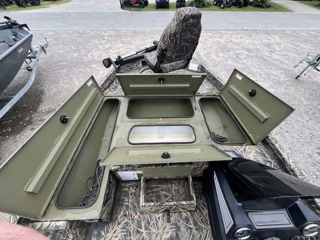 Slide: The Image of 2024 Lowe Stinger 175C boat interior with open storage compartments and camo seating. - 15