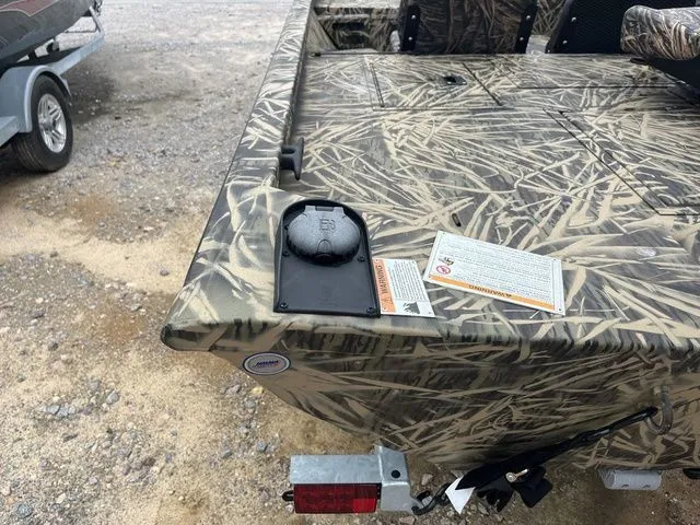 Slide: The Image of 2024 Lowe Stinger 175C boat with camouflage design, rear view on gravel surface. - 22