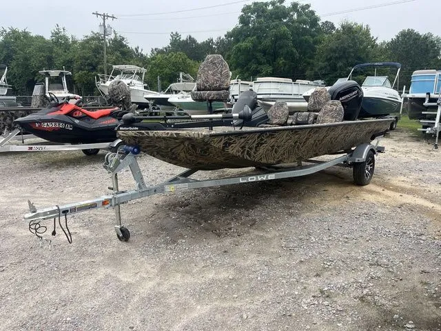 Slide: The Image of 2024 Lowe Stinger 175C boat on trailer, camo design, parked outdoors. - 3