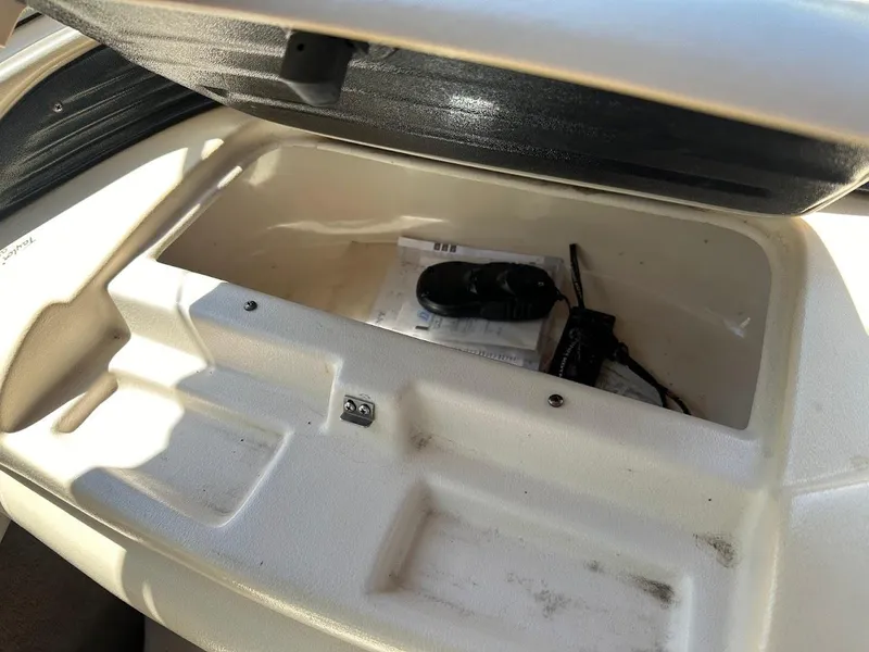 Slide: The Image of Open storage compartment in a 2001 Larson SEi 190 boat, containing documents and a device. - 19