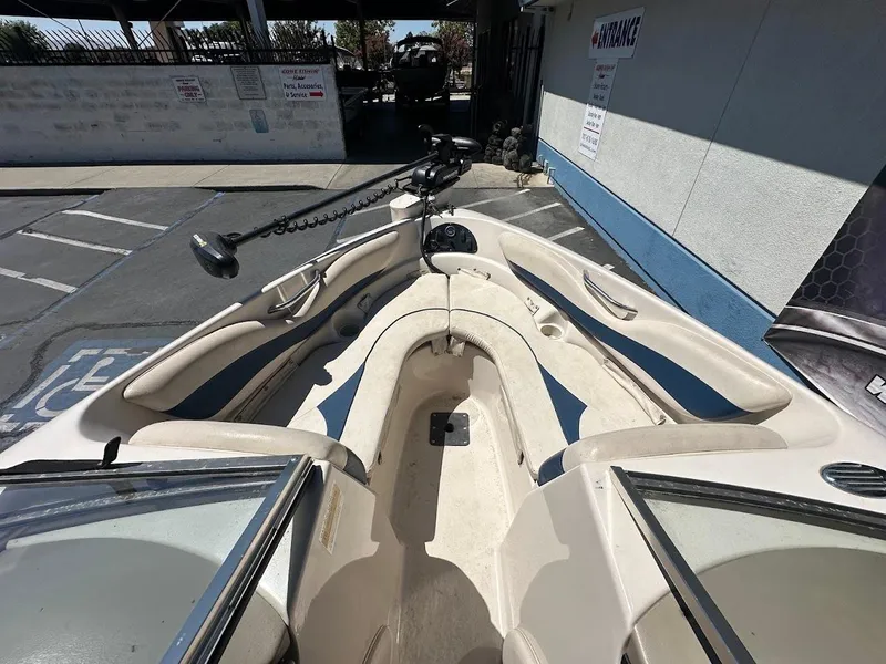 Slide: The Image of 2001 Larson SEi 190 boat interior with beige and blue seating, parked near a building. - 28