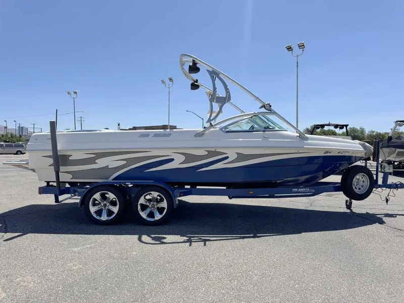 Slide: The Image of 2006 Custom B52 23 boat on trailer, blue and white design, parked outdoors. - 12