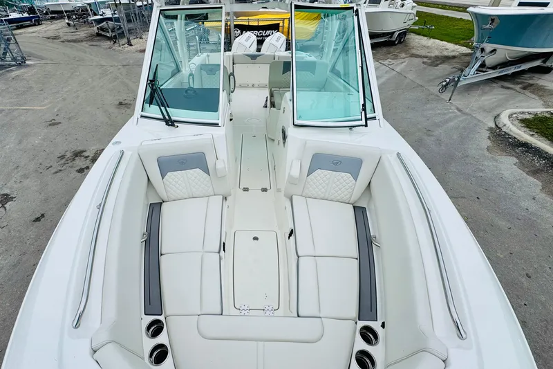Slide: The Image of 2026 Sailfish 276 DC boat interior with white seating and windshield, docked outdoors. - 17