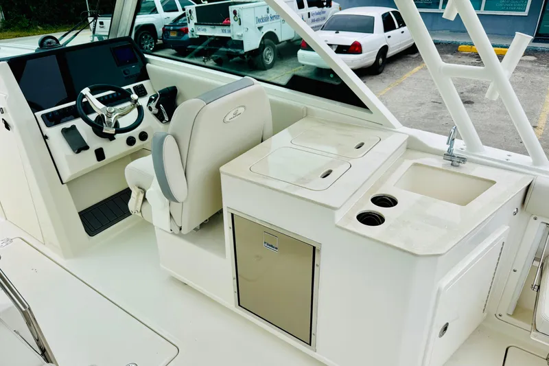 Slide: The Image of 2026 Sailfish 276 DC boat interior with helm, seating, sink, and storage compartments. - 32