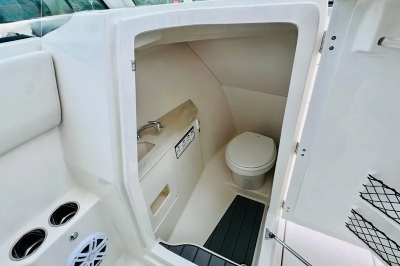 Slide: The Image of Interior of 2026 Sailfish 276 DC boat showing compact bathroom with toilet and sink. - 39