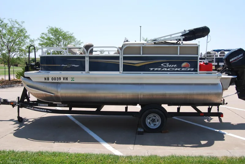 Slide: The Image of 2022 Sun Tracker Bass Buggy 16 XL pontoon boat on trailer in parking lot. - 2