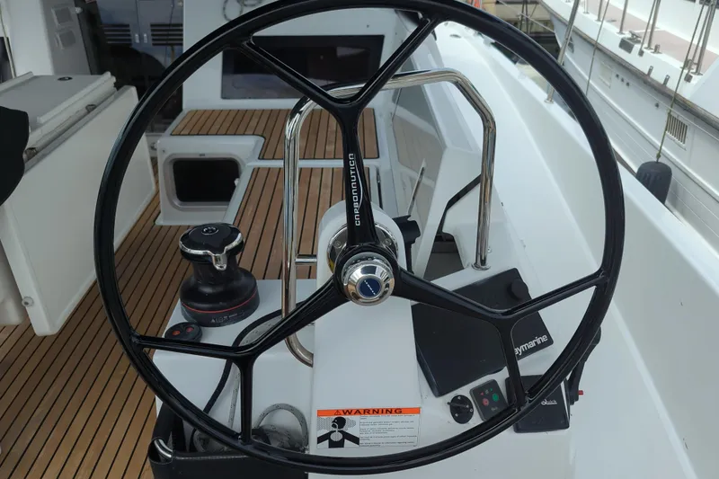 Slide: The Image of Steering wheel of 2021 Jeanneau Sun Odyssey 440 sailboat, featuring teak deck and navigation controls. - 18