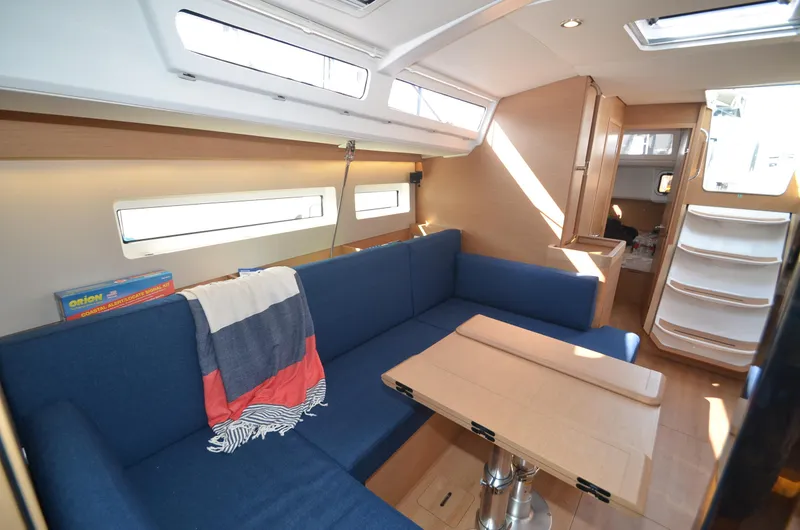 Slide: The Image of Interior of 2021 Jeanneau Sun Odyssey 440 sailboat with blue seating and wooden table. - 32