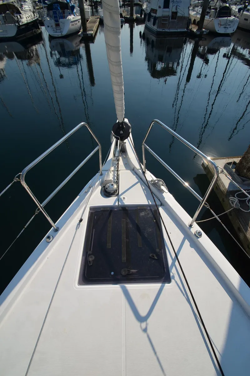 Slide: The Image of 2021 Jeanneau Sun Odyssey 440 sailboat bow in marina, surrounded by water and other boats. - 4