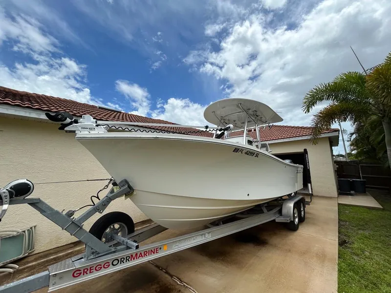 The Image of 2019 Regulator 23 boat on trailer, parked beside a house under a cloudy sky. - 0