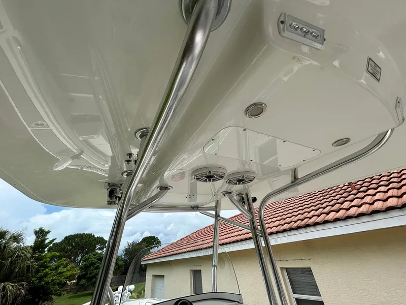 Slide: The Image of 2019 Regulator 23 boat T-top with speakers and lights, near a house with a tiled roof. - 13
