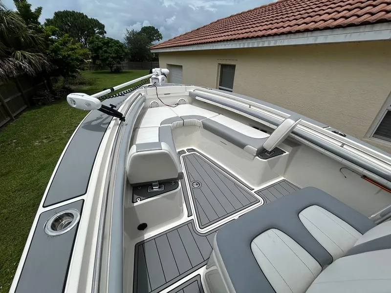 Slide: The Image of 2019 Regulator 23 boat interior with gray seating and deck, parked beside a house. - 15