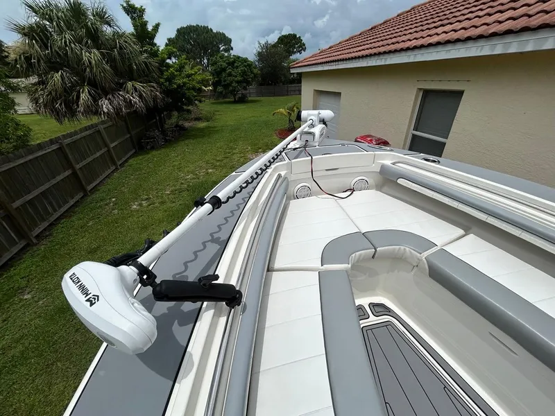 Slide: The Image of 2019 Regulator 23 boat with Minn Kota trolling motor, docked near a house and garden. - 17