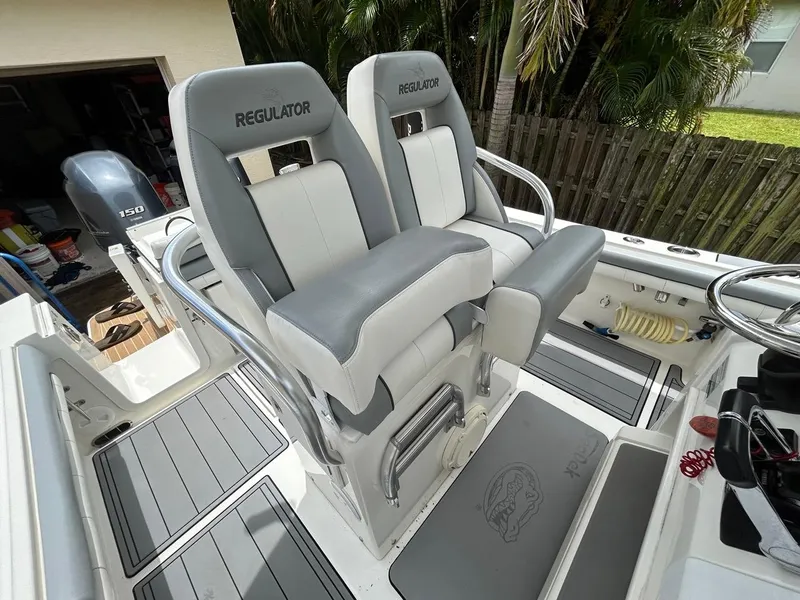 Slide: The Image of 2019 Regulator 23 boat interior with dual seats and Yamaha 150 engine in a tropical setting. - 21