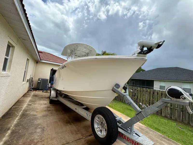 Slide: The Image of 2019 Regulator 23 boat on trailer beside house under cloudy sky. - 33