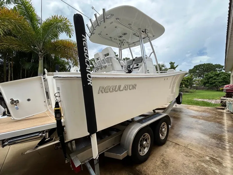 Slide: The Image of 2019 Regulator 23 boat on trailer, parked outdoors near palm trees. - 34
