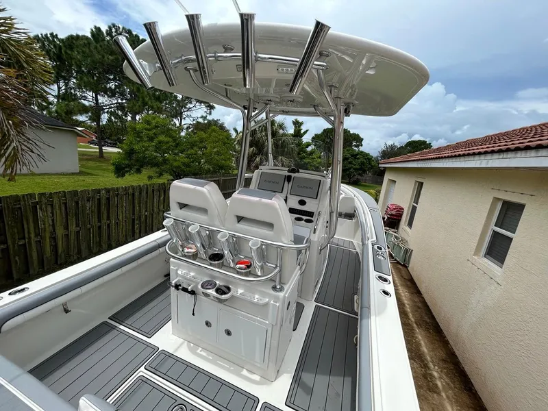 Slide: The Image of 2019 Regulator 23 boat with center console, rod holders, and dual seats, parked beside a house. - 9