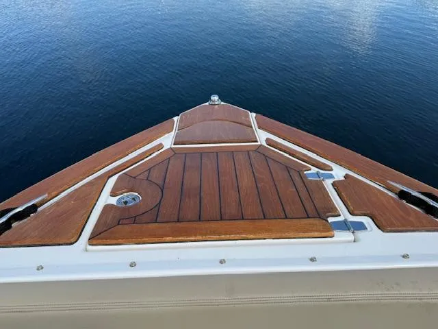 Slide: The Image of Bow of 2013 Regal 3200 Bowrider on calm water, featuring sleek wooden deck design. - 17