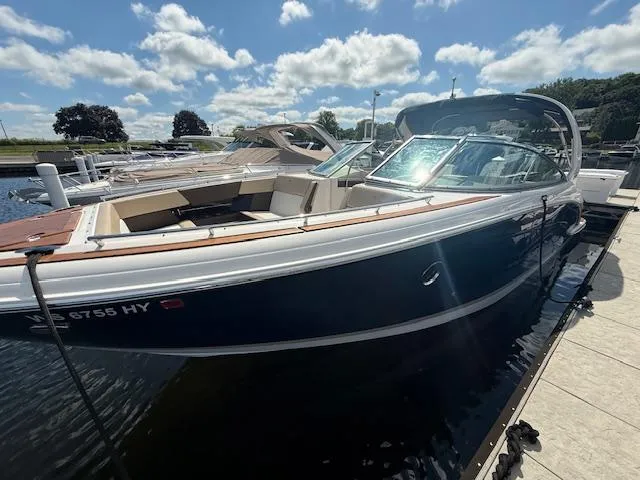 Slide: The Image of 2013 Regal 3200 Bowrider boat docked under a sunny sky. - 2