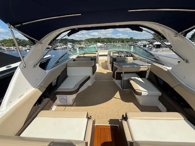 Slide: The Image of 2013 Regal 3200 Bowrider boat interior with spacious seating and canopy, docked at marina. - 4