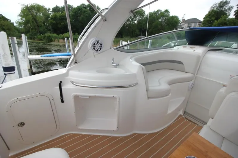 Slide: The Image of 2006 Chaparral Signature 290 boat interior with seating and sink, docked by a lake. - 8