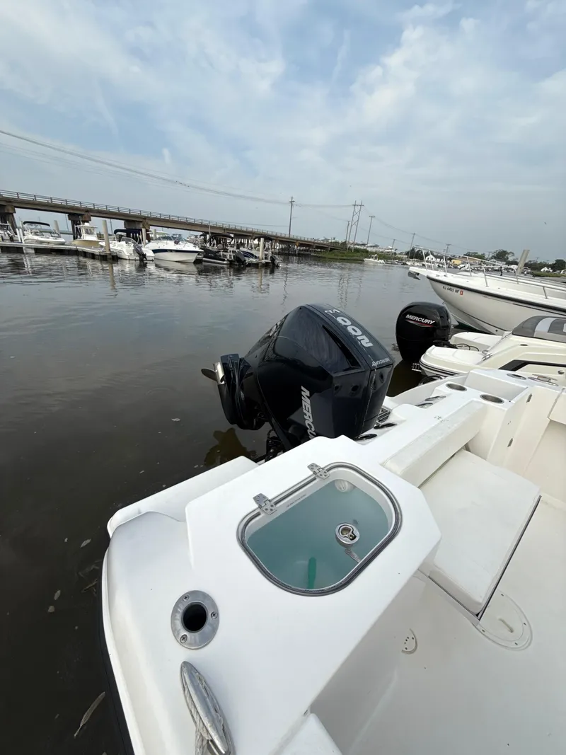 Slide: The Image of 2024 Aquasport 2200 Dual Console boat docked with outboard motor, under cloudy sky. - 7