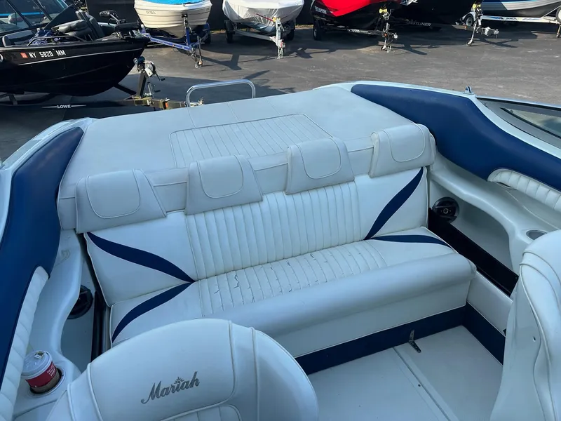 Slide: The Image of 1998 Mariah Z222 Shabah boat interior with white and blue seating, parked among other boats. - 2