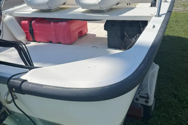 Slide: The Image of 2000 Boston Whaler Sport 13 boat with red fuel tank and seating, docked on grass. - 6