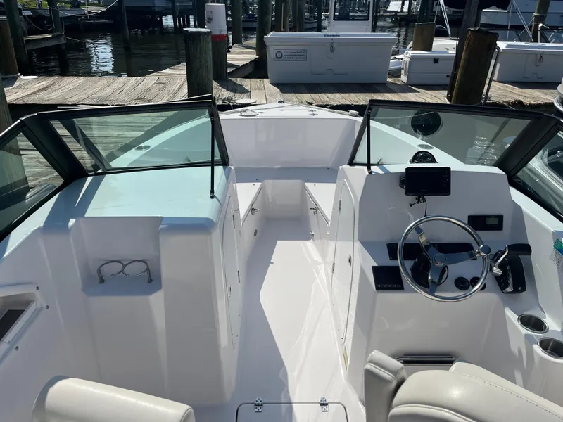 Slide: The Image of 2024 Aquasport 2200 Dual Console boat interior with steering wheel and seating at dock. - 3