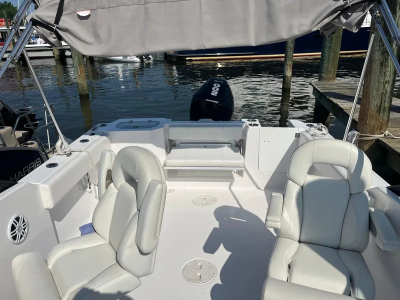 Slide: The Image of 2024 Aquasport 2200 Dual Console boat interior with white seating and canopy, docked at marina. - 5