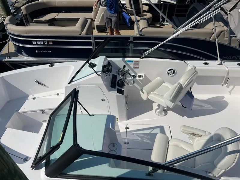 Slide: The Image of 2024 Aquasport 2200 Dual Console boat interior with white seating and steering wheel. - 6