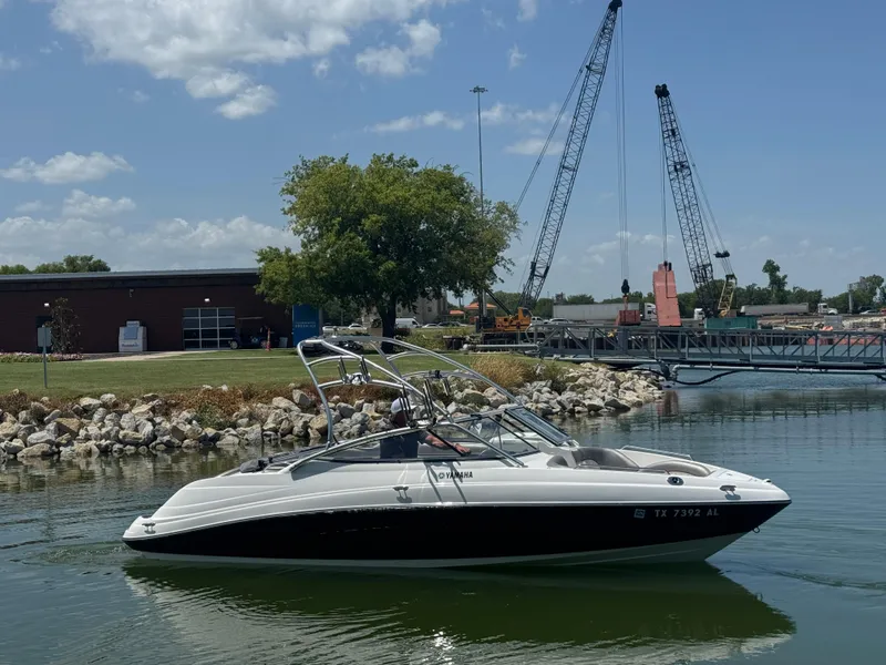 Slide: The Image of 2007 Yamaha AR230 HO boat on water near construction site with cranes. - 1
