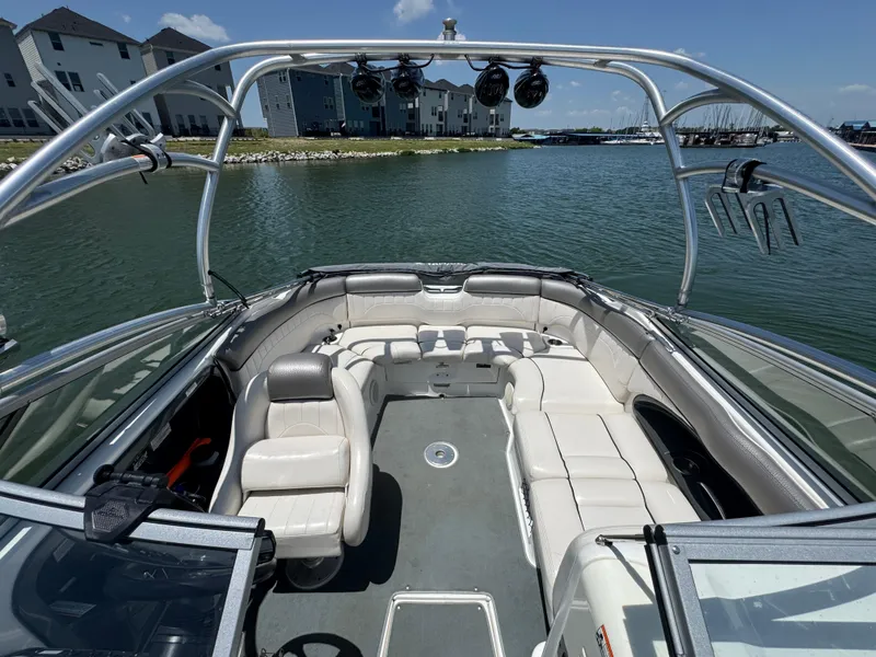 Slide: The Image of 2007 Yamaha Boats AR230 HO interior with seating, on a calm lake near modern buildings. - 13