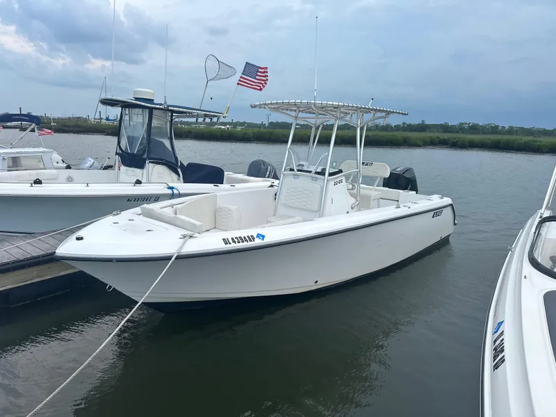 Slide: The Image of 2023 Aquasport 2200 Center Console boat docked on a calm waterway. - 0