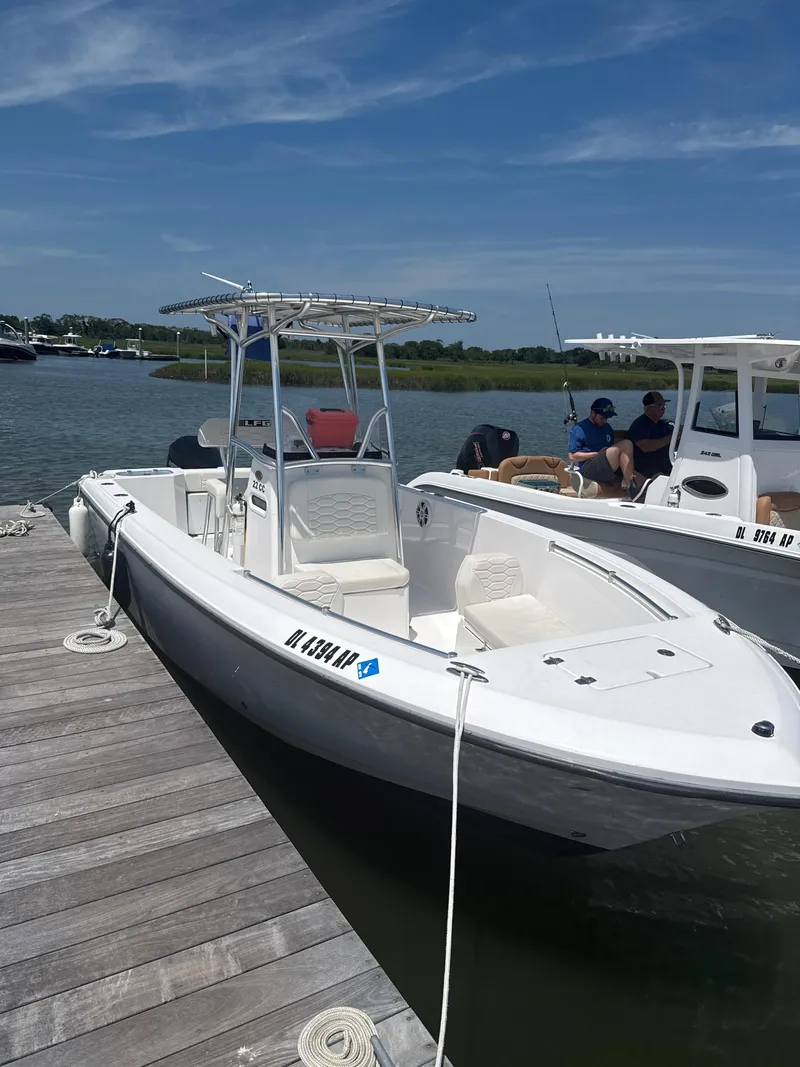 Slide: The Image of 2023 Aquasport 2200 Center Console boat docked on a sunny day. - 1