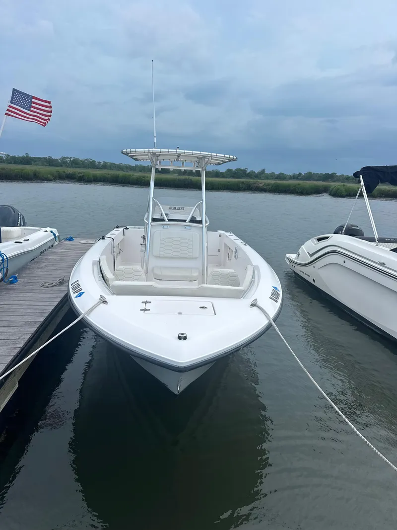 Slide: The Image of 2023 Aquasport 2200 Center Console boat docked by the water with American flag. - 3