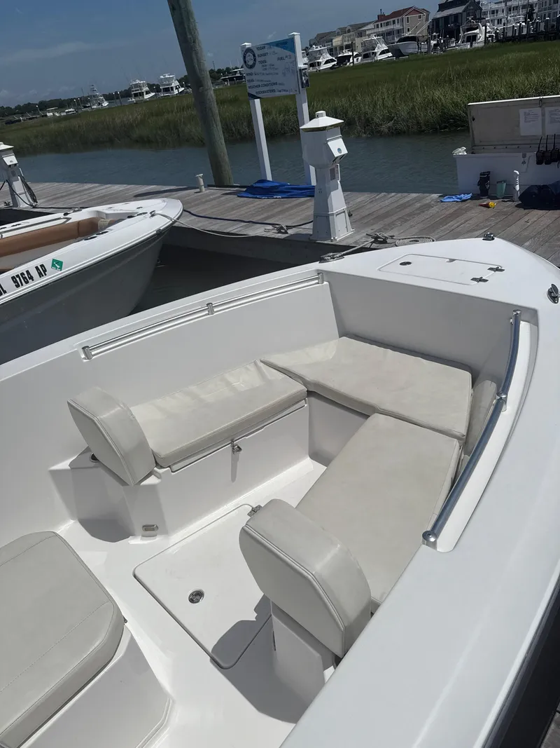 Slide: The Image of 2023 Aquasport 2200 Center Console boat with cushioned seating at dockside. - 6
