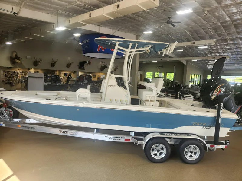 The Image of 2025 Pathfinder 2200 TRS boat displayed indoors on a trailer. - 0