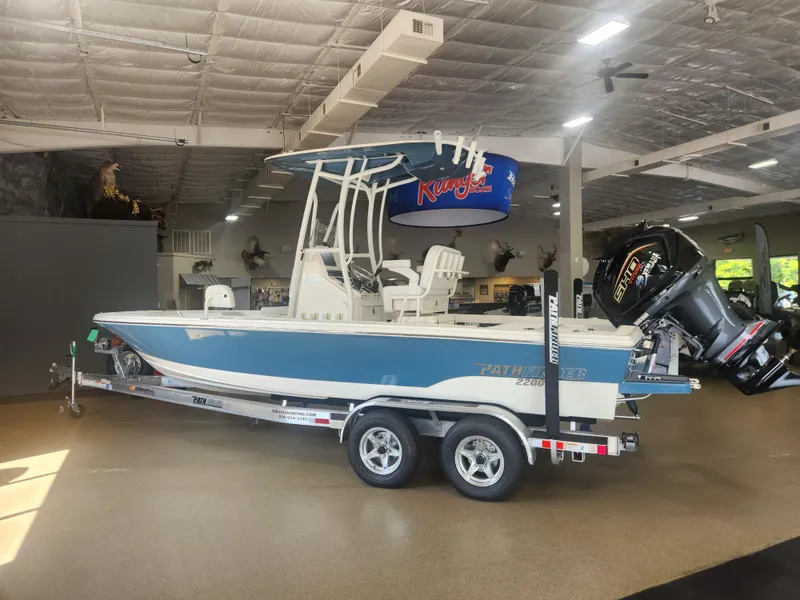 Slide: The Image of 2025 Pathfinder 2200 TRS boat on trailer in showroom, featuring sleek design and powerful engine. - 3