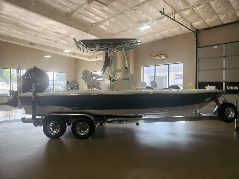 Slide: The Image of 2025 Pathfinder 2200 TRS boat on trailer in showroom, side view. - 8