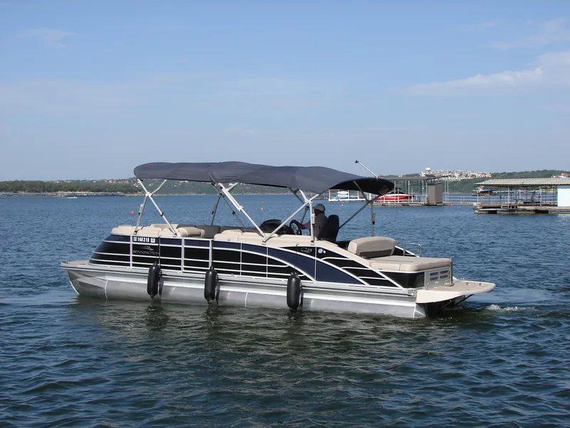 Slide: The Image of 2019 Bennington Q 25 QSBIO pontoon boat cruising on a lake under clear skies. - 2
