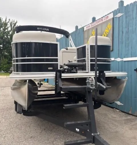 Slide: The Image of 2021 Sylvan Mirage 820 Cruise pontoon boat on trailer, parked near blue fence. - 2