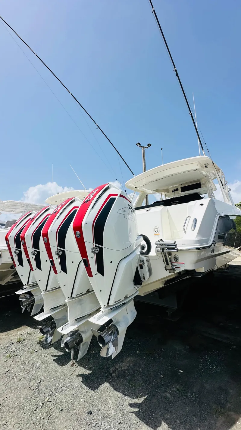 The Image of 2021 Boston Whaler 420 Outrage with four powerful outboard engines, docked under a clear blue sky. - 1